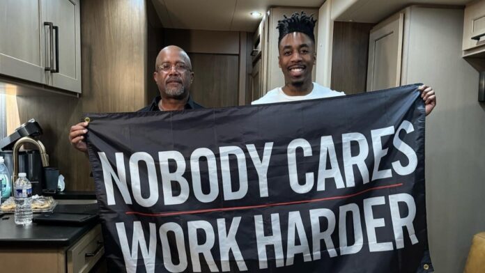 an image of is Dax and Darius Rucker holding a sign saying Nobody Cares Work Harder